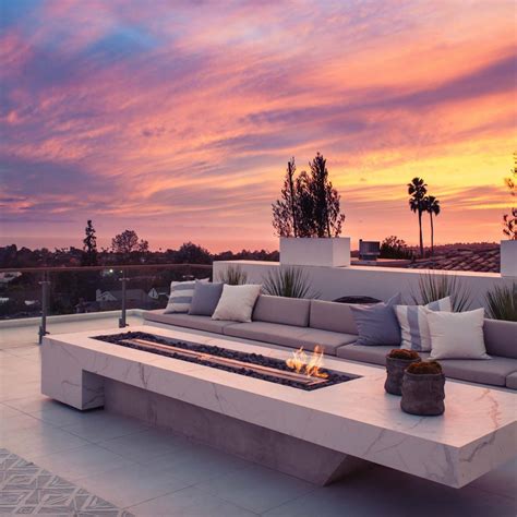 a couch sitting on top of a white tiled floor next to a fire pit under a purple sky