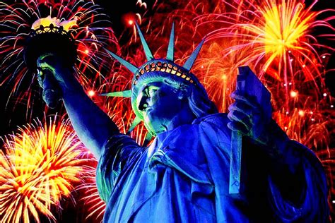 a man standing next to the statue of liberty with fireworks in the sky behind him