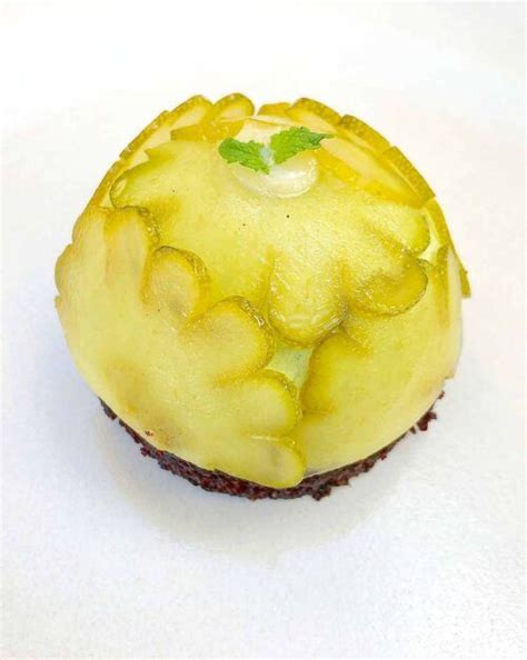 a cupcake covered in yellow frosting on top of a white table