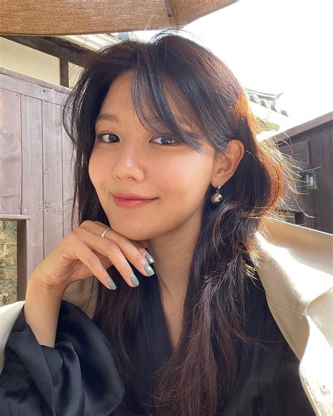 a woman with long black hair and blue nail polish posing for a photo under an umbrella