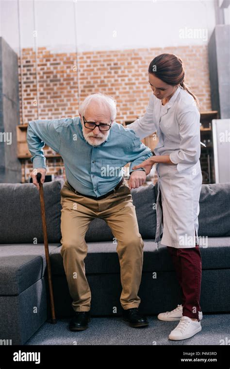 Doctor assisting male patient with cane Stock Photo - Alamy