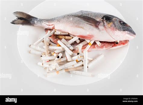 top view of gutted fish near cigarette ends on white, ecology concept Stock Photo - Alamy