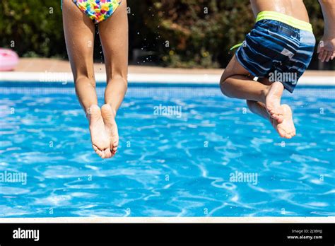 Two little kids jumping into a swimming pool. Leg detail Stock Photo - Alamy