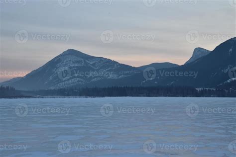 Pink Sunrise over a snowy mountain peak with frozen lake in the ...