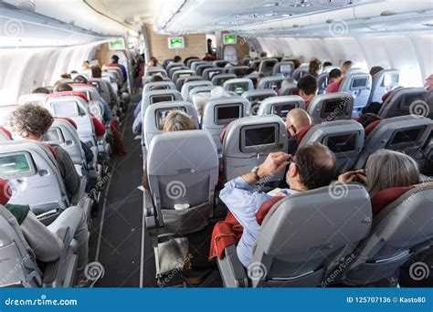 Interior of Large Commercial Airplane with Passengers on Their Seats during Flight. Editorial ...