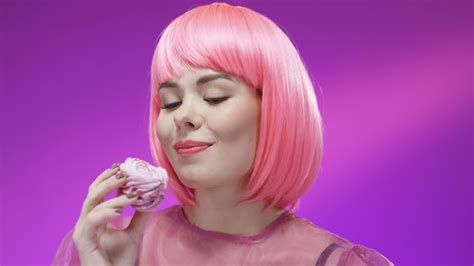 Free stock video - Close up of cute woman eating little cake with pink cream and smiling