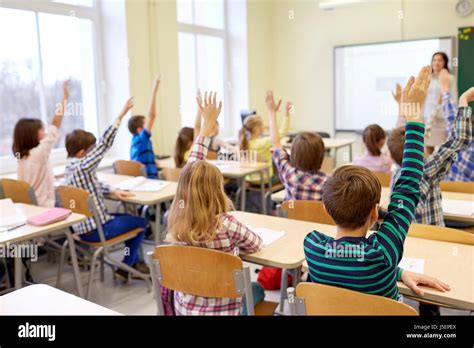 group of school kids raising hands in classroom Stock Photo - Alamy