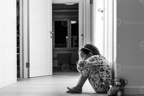 Sad little girl sitting near the wall 16478528 Stock Photo at Vecteezy