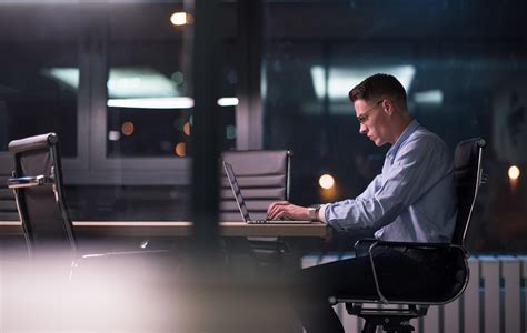 man working on laptop in dark office 12440130 Stock Photo at Vecteezy