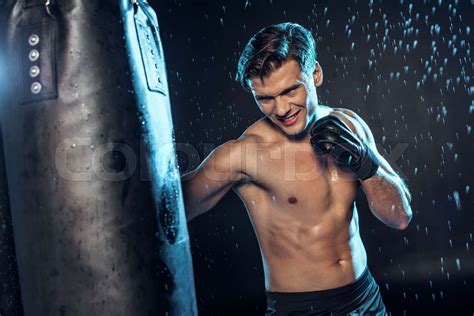 Boxer training with punching bag under water drops on black | Stock ...