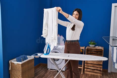 Young Beautiful Hispanic Woman Holding Clothes Ironing Clothes at Laundry Room Stock Image ...