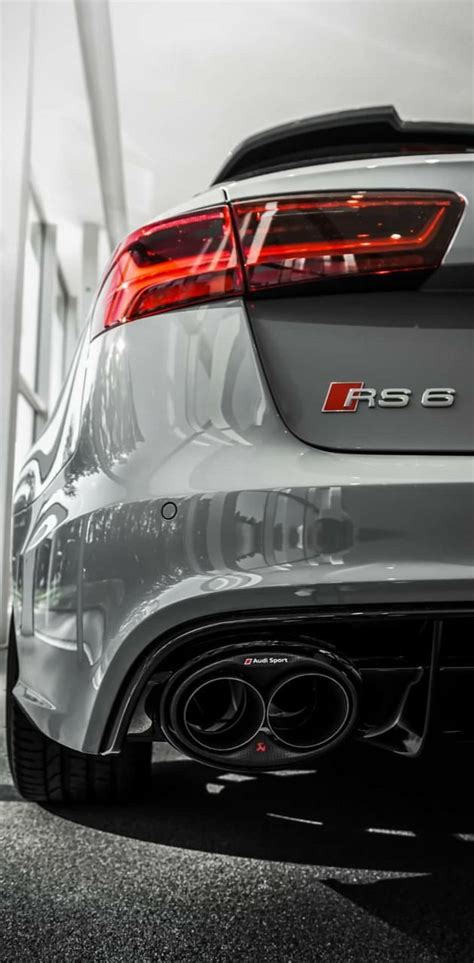 the rear end of a silver car parked in front of a building