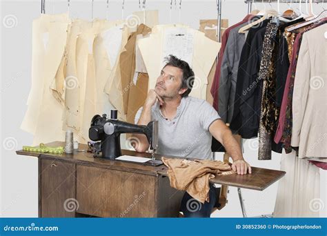 Mature Male Tailor Thinking while Sitting at Sewing Machine with Fabric ...