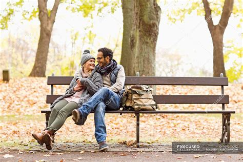 Smiling couple sitting on park bench — happiness, leisure - Stock Photo | #169023092