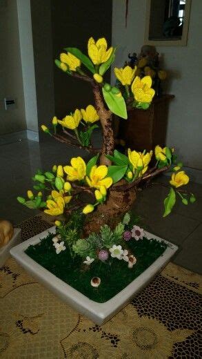 a bonsai tree with yellow flowers and green leaves