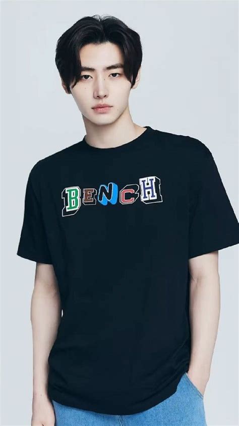 a young man wearing a black t - shirt with the word bench printed on it