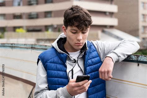 A teenage boy looking into a phone with a sad face and having negative ...