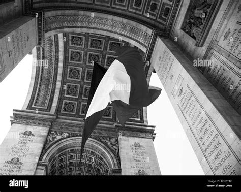 French flag waving under Arc de Triomphe in honor of VE day. Paris, France. Black white historic ...