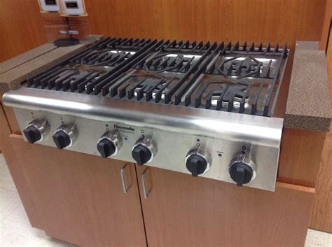 a stainless steel stove top oven sitting inside of a kitchen next to a wooden cabinet