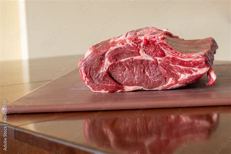 A large raw beef prime rib roast seasoned on a white plastic cutting ...