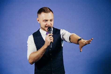 The entertainer. Young elegant talking man holding microphone, Isolated on blue background ...