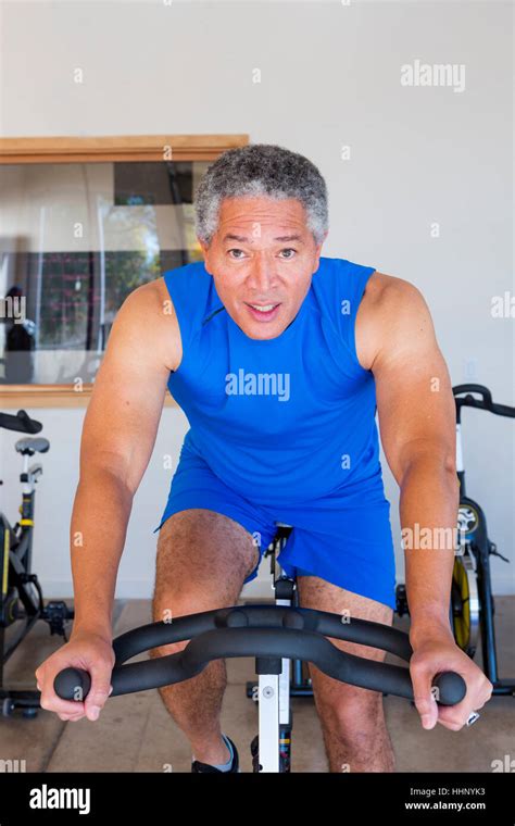 Mixed Race man riding stationary bicycle in gymnasium Stock Photo - Alamy