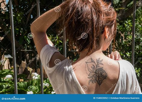 A Young Red-haired Tourist with an Arum-lily Tattoo on Her Back Looks at a Garden with the Same ...