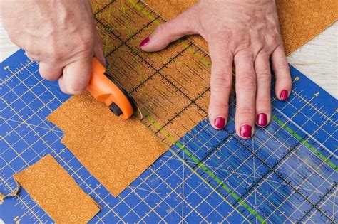 Free Photo | Close-up of a person cutting fabric pieces by rotary cutter on mat using ruler