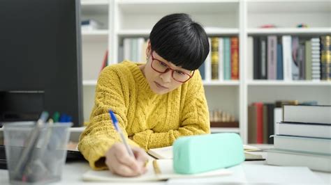 Premium Photo | Young chinese woman student writing on notebook ...