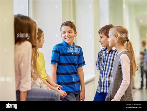 group of smiling school kids talking in corridor Stock Photo - Alamy