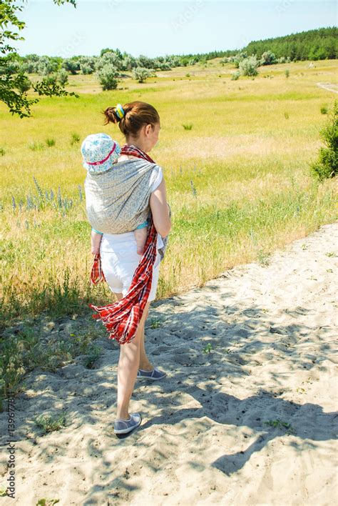 Mother carrying her little child in a baby sling Stock Photo | Adobe Stock