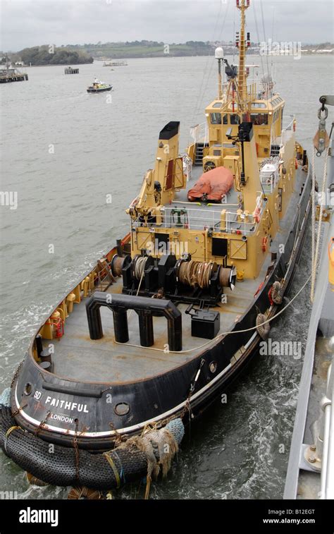 Dockyard tug "Faithful" manoeuvering alongside a Royal Navy Type 23 frigate in Devonport England ...