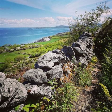 a stone wall on the side of a hill overlooking water and land in the ...