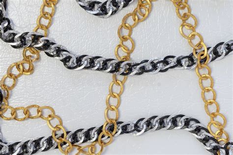 Silver and Gold Color Chains. Chains on White Leather Background Stock ...