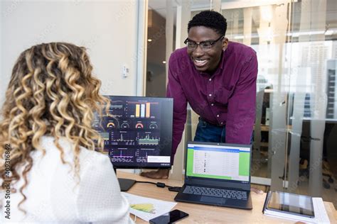 Happy business people talking at computer and laptop in office Stock Photo | Adobe Stock