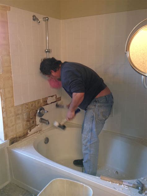 a man is cleaning the bathtub in his bathroom while he works on fixing the faucet