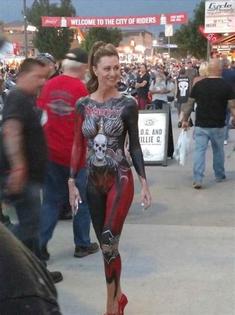 a woman in black and red bodysuit walking down the street with people ...