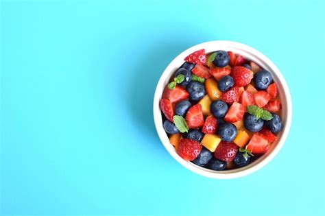 Premium Photo | Fruit salad in a white cup on a soft blue background ...