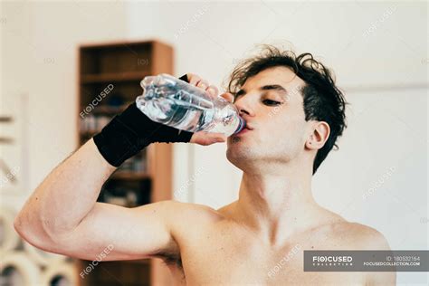 Man drinking water from bottle in gym — Focus On Foreground, refresh ...