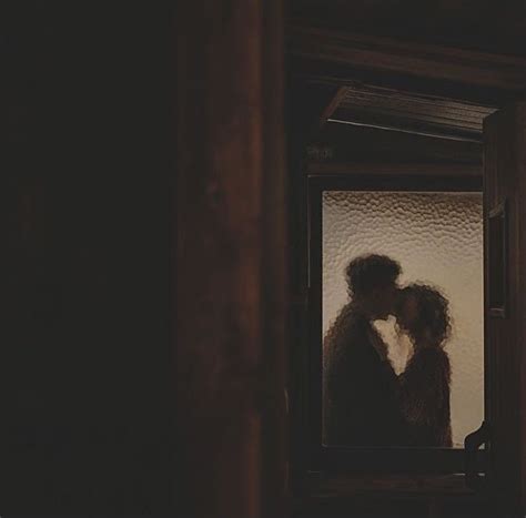 two people are kissing in front of a window