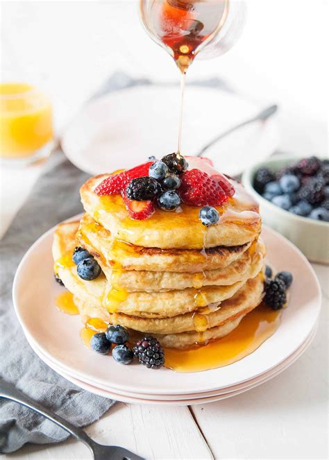 a stack of pancakes with syrup being drizzled over them and topped with ...