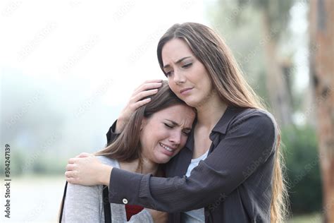 Sad woman crying and a friend comforting her Stock Photo | Adobe Stock