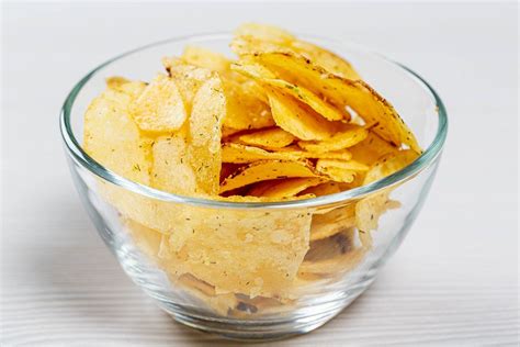 Potato chips in a glass bowl on a white table - Creative Commons Bilder