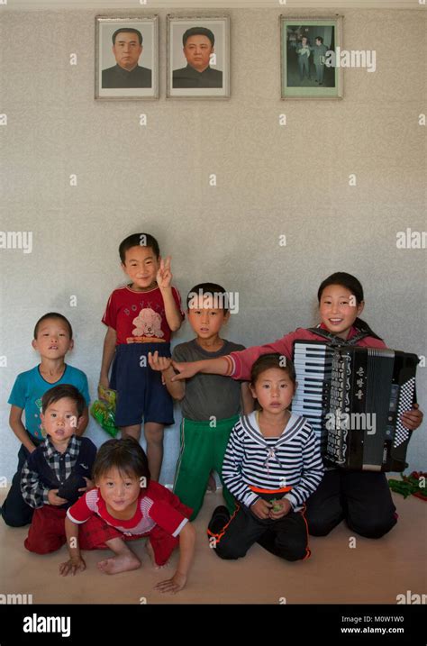 Group of children posing under Kim Jong il and Kim il Sung portraits in ...