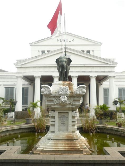 a statue in front of a building with a flag on it's roof and columns