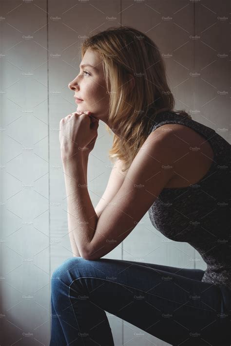 Thoughtful woman sitting with hand on chin | Stock Photos ~ Creative Market