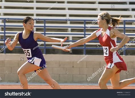 Female Runners Passing Baton In Relay Race Stock Photo 111588257 ...