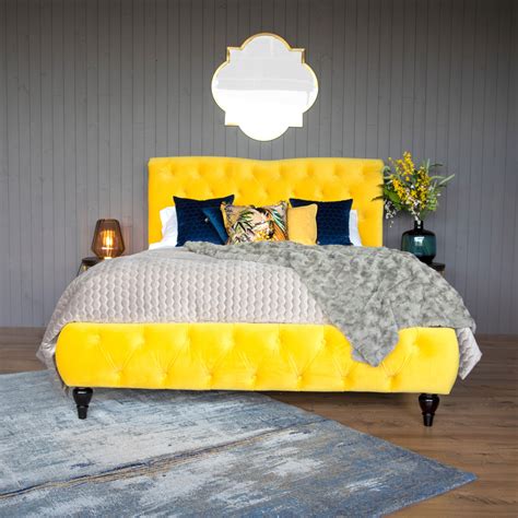 a bed with yellow headboard and pillows on top of it next to a blue rug
