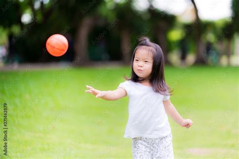 Foto Stock Excited little cute girl playing orange ball on soccer field outdoors. Adorable kid ...