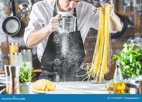 Chef Making Spaghetti Noodles with Pasta Machine on Kitchen Table with Some Ingredients Around ...